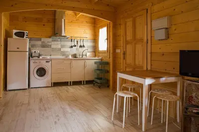 a kitchen with a refrigerator and a table and stools at Casita de madera junto al mar in El Puerto de Santa María