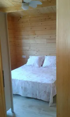 a bedroom with a white bed with a wooden wall at Casita de madera junto al mar in El Puerto de Santa María