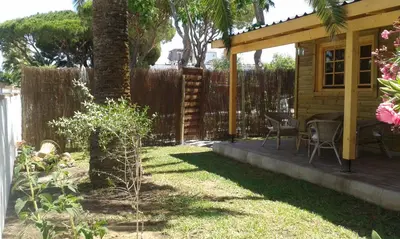a backyard with a wooden cabin with a table and chairs at Casita de madera junto al mar in El Puerto de Santa María