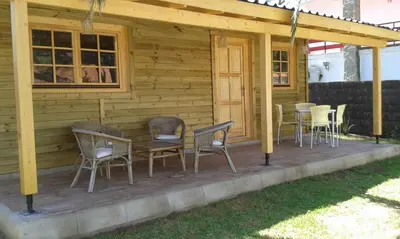 a wooden cabin with chairs and a table on a deck at Casita de madera junto al mar in El Puerto de Santa María