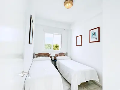 two beds in a white room with a window at Retama Golf Nº 55 by Fontanilla Del Mar Holidays Rentals in Chiclana de la Frontera