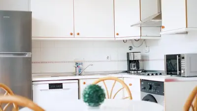 a kitchen with white cabinets and a table with a plant at Retama Golf Nº 55 by Fontanilla Del Mar Holidays Rentals in Chiclana de la Frontera