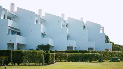 a white building with a hedge in front of it at Retama Golf Nº 55 by Fontanilla Del Mar Holidays Rentals in Chiclana de la Frontera