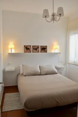 a bed in a bedroom with two lamps on the wall at Chipiona Acogedor in Chipiona