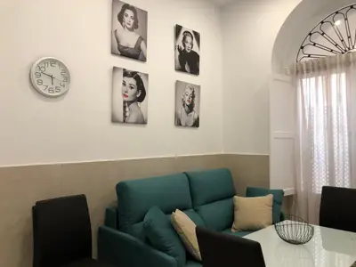 a living room with a blue couch and a clock at Jano PuertaTierra in Cádiz