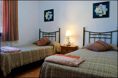 a room with two beds and a table with a lamp at Chalet con piscina privada in Conil de la Frontera