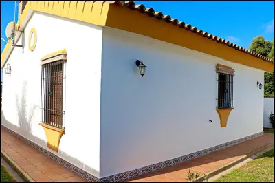 a white building with windows and a roof at Chalet con piscina privada in Conil de la Frontera