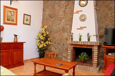 a living room with a stone fireplace and a table at Chalet con piscina en Roche Viejo in Conil de la Frontera