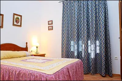 a bedroom with a bed and a blue and white curtain at Chalet con piscina en Roche Viejo in Conil de la Frontera