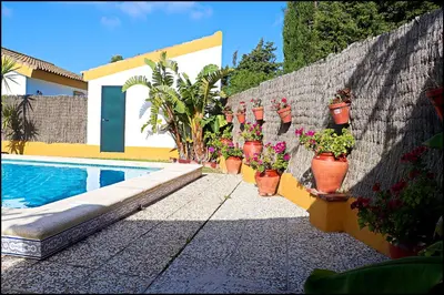a fence with potted plants next to a swimming pool at Chalet con piscina en Roche Viejo in Conil de la Frontera