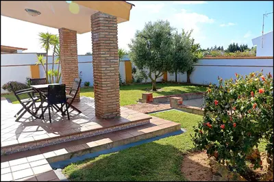 a patio with a table and chairs under an umbrella at Chalet con piscina en Roche Viejo in Conil de la Frontera