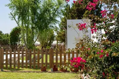 a wooden fence with pink flowers in a yard at Casa Huerta del Pitorreo in Conil de la Frontera