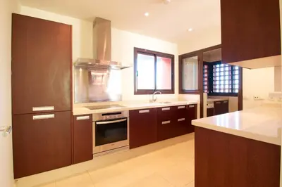 a kitchen with wooden cabinets and a stove top oven at Aparthotel Novo Resort in Chiclana de la Frontera