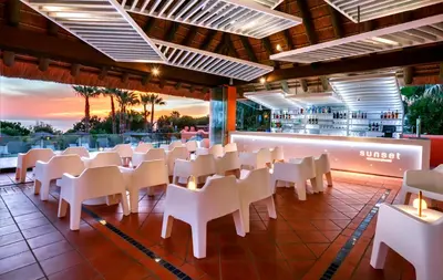 a restaurant with white chairs and a bar at Aparthotel Novo Resort in Chiclana de la Frontera