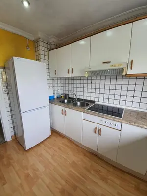 a kitchen with white cabinets and a white refrigerator at Precioso piso al lado de la playa in Cádiz