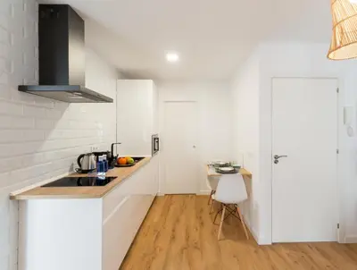 a white kitchen with a sink and a table at Bohórquez Rooms by Ático73 in Medina Sidonia