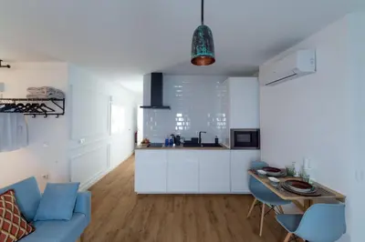 a white kitchen with a blue couch and a table at Bohórquez Rooms by Ático73 in Medina Sidonia