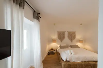 a bedroom with a bed and a tv and a window at Bohórquez Rooms by Ático73 in Medina Sidonia