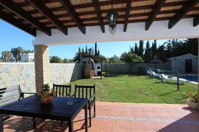 a black table and chairs on a patio with a yard at Albara in Conil de la Frontera