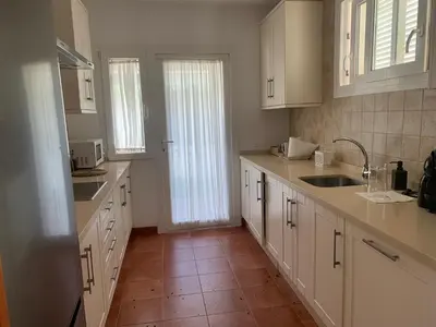 a kitchen with white cabinets and a tile floor at Villas La Barrosa in Chiclana de la Frontera
