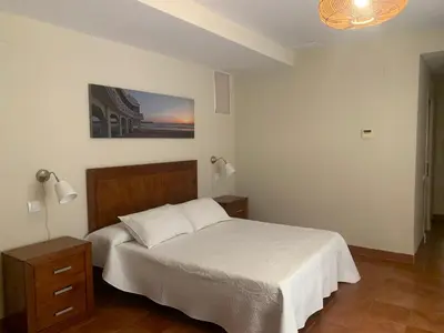 a bedroom with a white bed with a wooden headboard at Villas La Barrosa in Chiclana de la Frontera