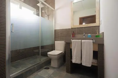 a bathroom with a toilet and a shower with towels at Villas La Barrosa in Chiclana de la Frontera