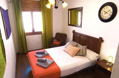 a bedroom with a bed and a clock on the wall at Apartamento Rústico_Centrico in El Puerto de Santa María