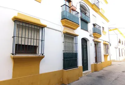 a white building with black barred windows on a street at Apartamento Rústico_Centrico in El Puerto de Santa María