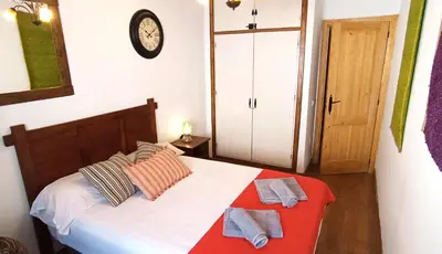 a bedroom with a bed and a clock on the wall at Apartamento Rústico_Centrico in El Puerto de Santa María
