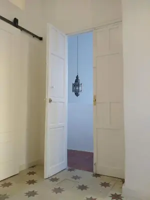 an empty room with white doors and a chandelier at Azafran Jerez apartamentos in Jerez de la Frontera