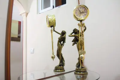 a gold clock and two women on a glass table at Apartamento SERAFÍN de la Caleta in Cádiz