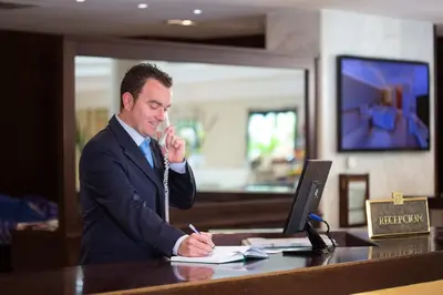 a man talking on the phone at a desk with a laptop at Hipotels Sherry Park in Jerez de la Frontera