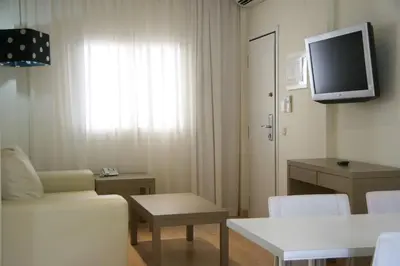 a living room with a couch and a tv on the wall at Aparthotel Novo Sancti Petri in Chiclana de la Frontera