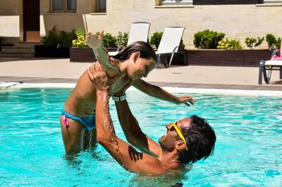 two men are playing in a swimming pool at Aparthotel Novo Sancti Petri in Chiclana de la Frontera