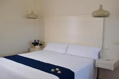 a bedroom with a white bed with two pillows at Aparthotel Novo Sancti Petri in Chiclana de la Frontera