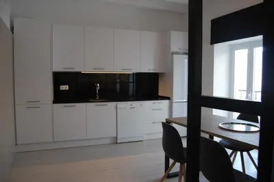 a kitchen with white cabinets and a table with chairs at Guesting Basílica in Jerez de la Frontera