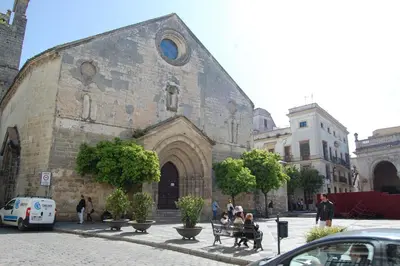 a group of people sitting on benches in front of a building at Guesting Basílica in Jerez de la Frontera