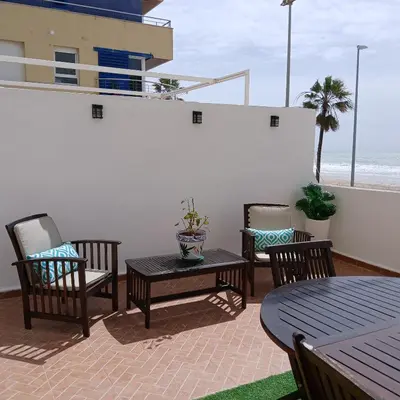 a patio with three chairs and a table and a table and chairsktop at AMAZING FRONTAL BEACH APARTMENT #Traveller's Awards2023 in Cádiz