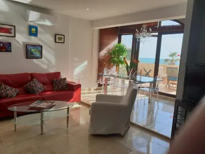 a living room with a red couch and a glass table at AMAZING FRONTAL BEACH APARTMENT #Traveller's Awards2023 in Cádiz