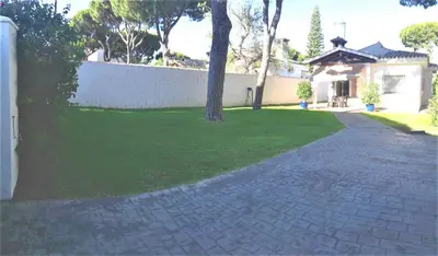 a house with a yard with a brick driveway at Chalet Costa de la Luz - La Barrosa in Chiclana de la Frontera