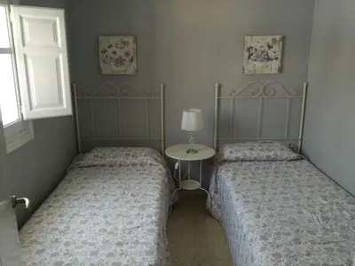 two beds in a bedroom with a table and a window at Carretera Pinar de los Franceses JAZMIN in Chiclana de la Frontera