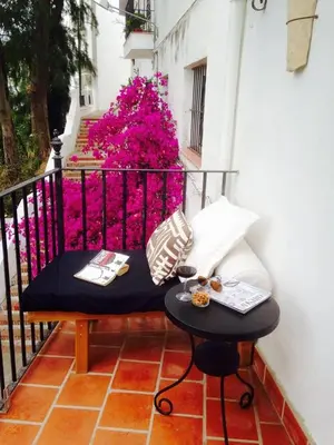a bench sitting on a balcony with pink flowers at Casa MariSol in Arcos de la Frontera