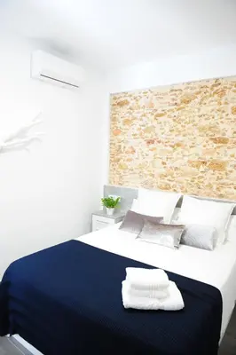 a bedroom with a blue bed with a brick wall at LUZ DEL FARO in Cádiz