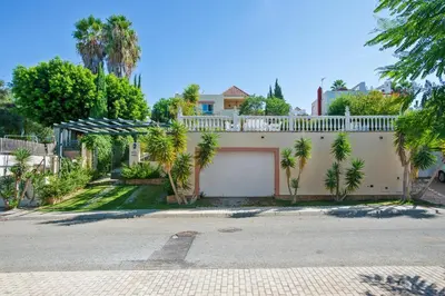 a house with a white fence and palm trees at Charming villa in Sanlúcar de Barrameda with private pool in Sanlúcar de Barrameda