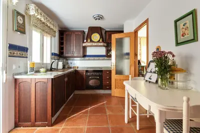 a kitchen with wooden cabinets and a table and a counter at Charming villa in Sanlúcar de Barrameda with private pool in Sanlúcar de Barrameda