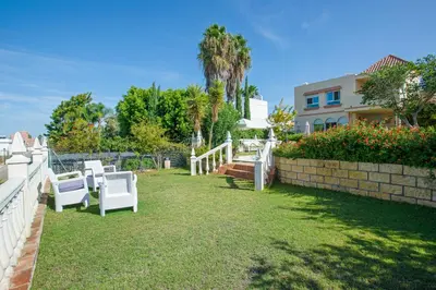 a yard with two white chairs and a fence at Charming villa in Sanlúcar de Barrameda with private pool in Sanlúcar de Barrameda