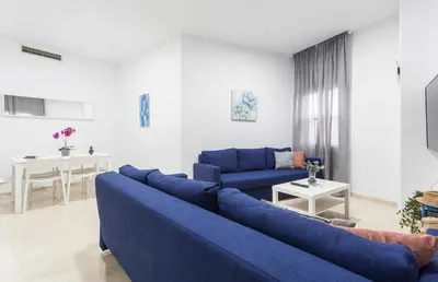 a living room with a blue couch and a table at Centro 4 Rooms 3 baños Parking in Jerez de la Frontera