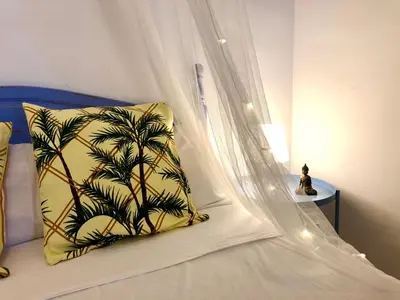 a bed with a canopy and a pillow with a palm tree at GATU Verano en la playa con parking, wifi, piscina in El Puerto de Santa María