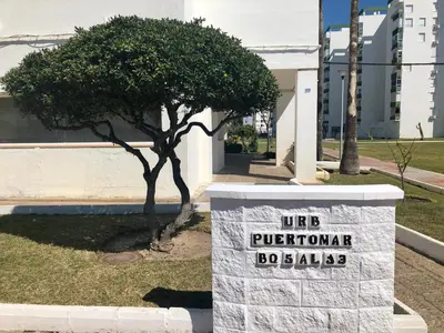 a sign in front of a building with a tree at GATU Verano en la playa con parking, wifi, piscina in El Puerto de Santa María