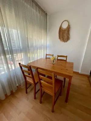 a wooden table and chairs in a room with a window at GATU Verano en la playa con parking, wifi, piscina in El Puerto de Santa María
